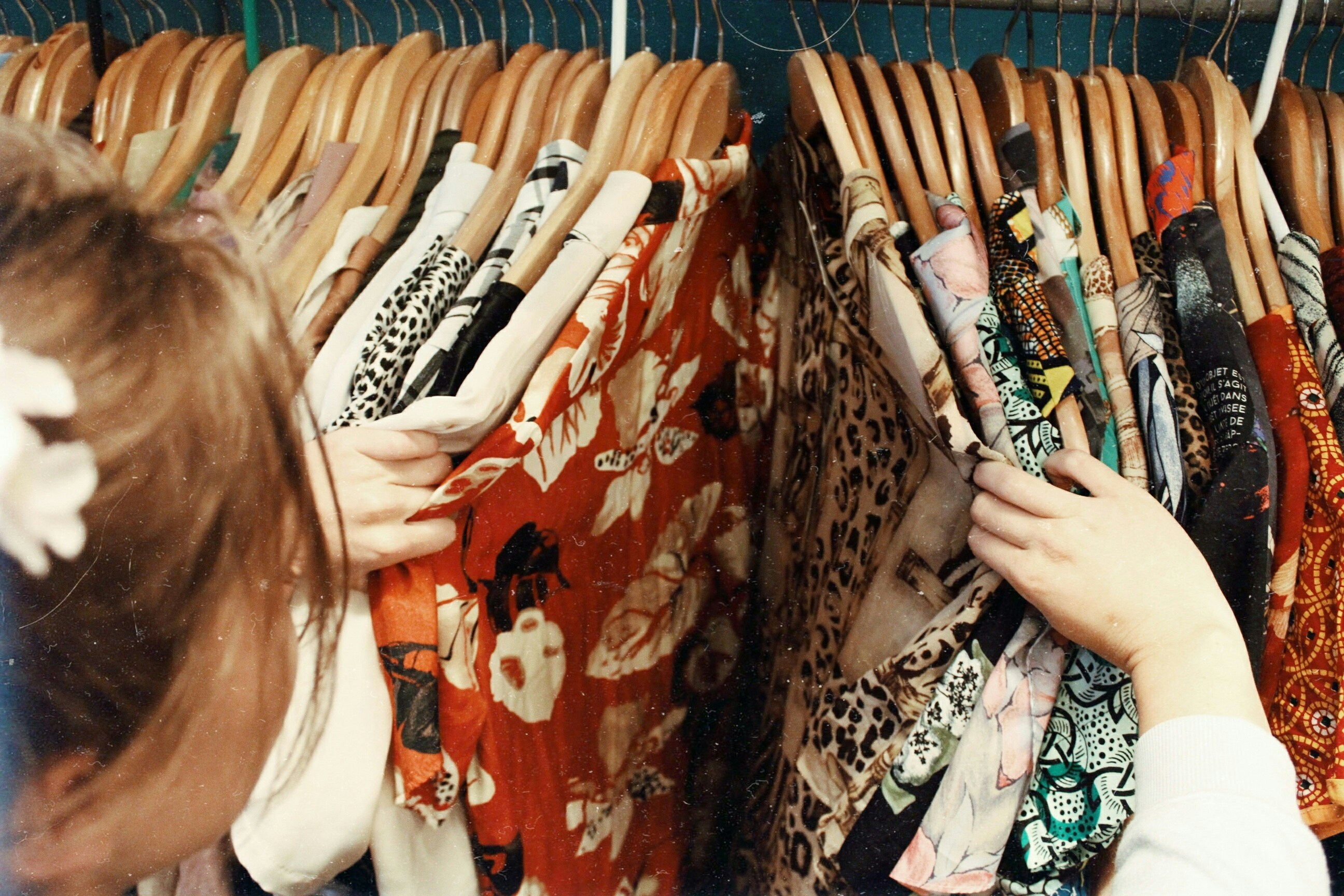 woman sorting through clothes on hangers